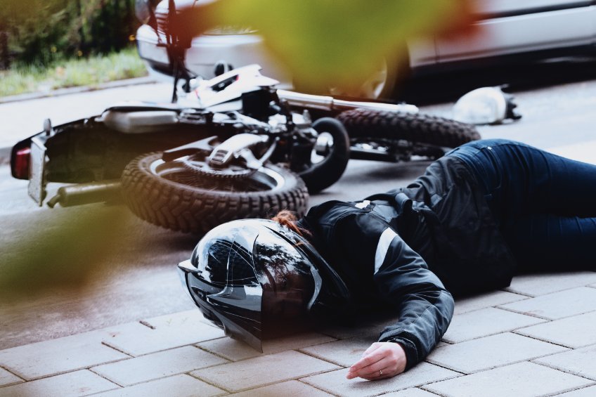 Jeune conductrice de moto allongée à côté de son véhicule après un accident